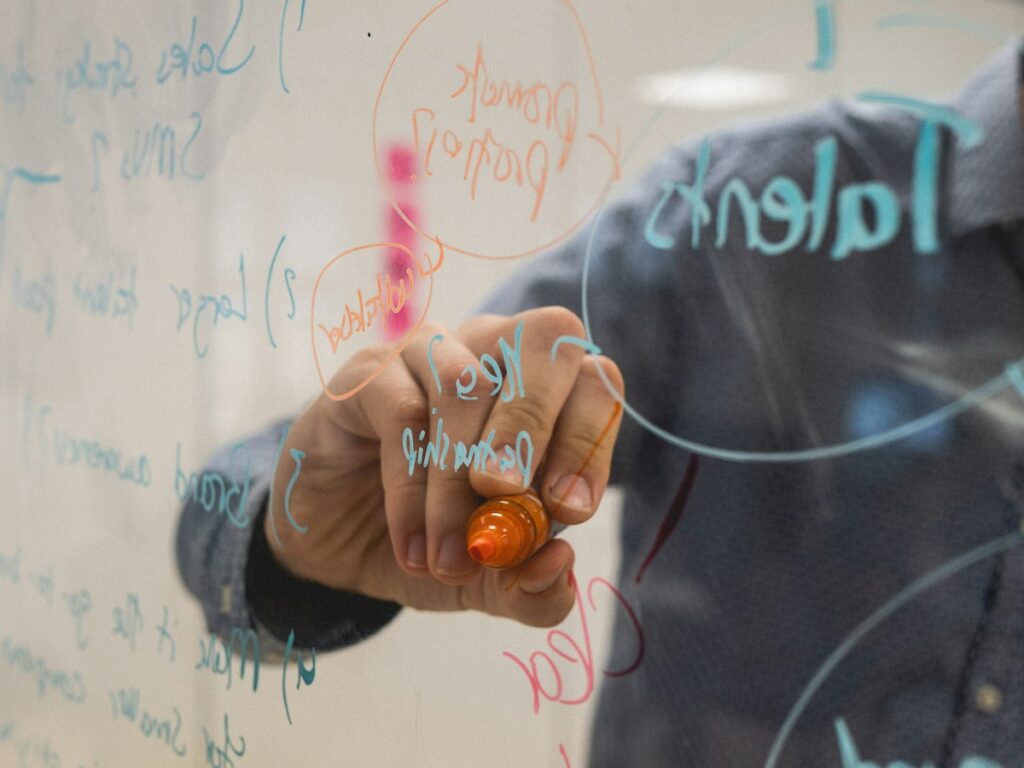 Marketing strategy planning session with diagrams on a glass whiteboard
